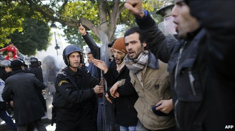 A policeman holds back protesters in Tunis, Tunisia (17 Jan 2011)