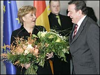 New Chancellor Angela Merkel receives flowers from the outgoing Gerhard Schroeder