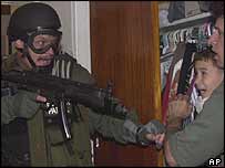 US federal officer pointing gun at Elian and man holding him