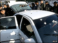 Palestinian security officers inspect the car hit in the attack