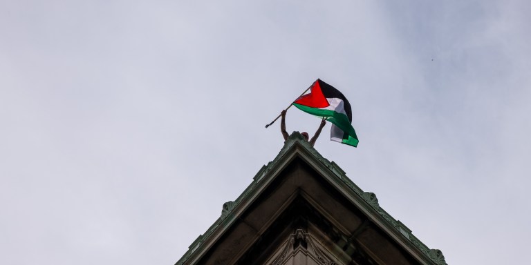 NEW YORK, NEW YORK - APRIL 30:  A Pro-Palestinian supporter waves a Palestinian flag from the roof of Hamilton Hall as they continue to demonstrate with a protest encampment on the campus of Columbia University on April 30, 2024 in New York City. All classes at Columbia University have been held virtually today after school President Minouche Shafik announced a shift to online learning in response to recent campus unrest.  (Photo by Spencer Platt/Getty Images)