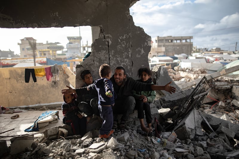 Palestinian Muhammad Al Durra with his children in the ruins of a house in Rafah where they sheltered on January 11, 2024. EPA