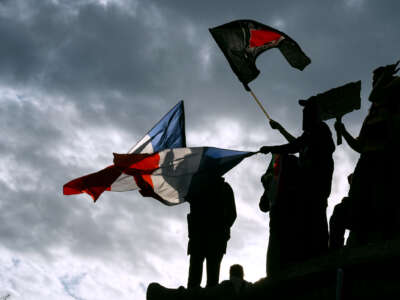 People wave the Antifascist and French flags at an outdoor rally