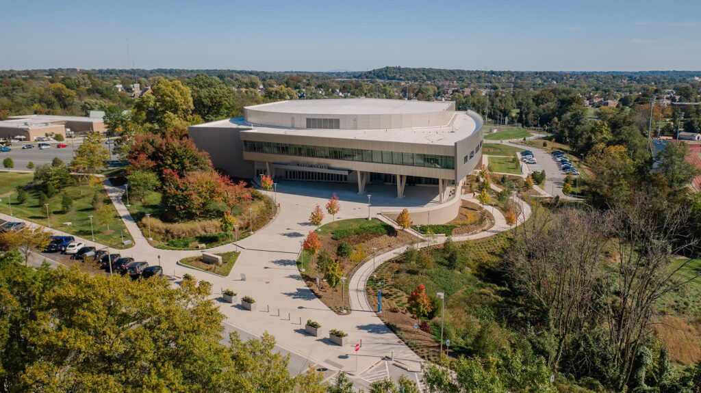 A drone image shows UMBC's campus from above, highlighting the curved entrance paths leading to Chesapeake Employers Insurance Arena.