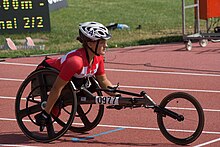 White woman with a red and white top in a black wheelchair.