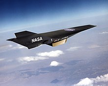 Artist's conception of black, wingless jet with pointed nose profile and two vertical stabilizers traveling high in the atmosphere.