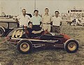 Legendary race driver Johnny Coy at Islip Speedway behind the wheel of the Vitucci midget number 10. Car owner Angelo Vitucci is standing (second from left).