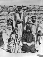Several women dressed in Arab clothing and posed in front of a wall