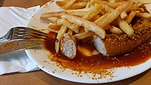 Currywurst lightly topped with curry and served with French fries.