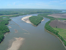 Aerial view of a brownish river winding through an agricultural valley