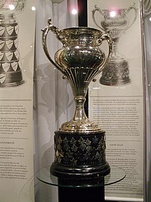 Silver bowl trophy with two large handles, mounted on a black plinth.