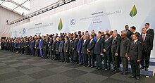 Une centaine de femmes et d'hommes en costumes disposés sur trois rangées posant pour une photo.