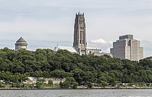 A landscape of Riverside Park; behind the park's trees is the tower of Riverside Church, at center