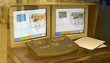 Photo of airport bag screening equipment. Two monitors are shown, and the images on the screens are color x-rays of carry-on baggage.