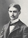 A photograph Stephen Crane in a suit, with parted hair and a mustache
