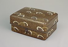 Box with design of wheels in gold and white on black background all over.