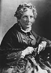 A photograph of a seated Harriet Beecher Stowe, wearing a dress and a shawl