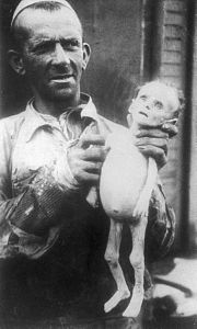 Home mostrant el cadàver d'un nadó mort de fam al gueto de Varsòvia, 1942