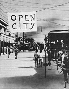 A Manila street with a large sign hanging over it which reads "open city"