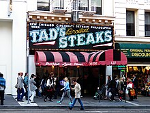 Sign reads "New York / Chicago Cincinnati / Detroit / Philadelphia / TAD'S Broiled STEAKS, surrounded by lights.