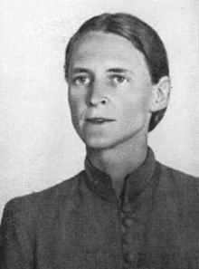 A grainy black-and-white photograph of a woman with hair tightly drawn about her hair wearing a shirt with a high collar and buttons