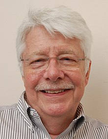 A white-haired man with moustache and glasses