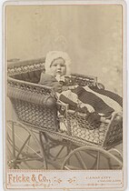 Portrait of child in wicker stroller, 1894.
