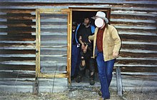 Photograph of a handcuffed Kaczynski being led from a cabin by a man