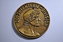 Obverse of a gold-colored commemorative medal for the 50th Infantry Division. A soldier wearing a laurel-fitted helmet is underneath text reading '50.Infanterie-Division'.