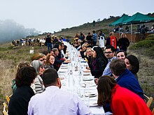 A large group of diners, all seated at one long table