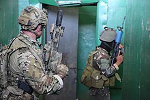 Colour photo of two soldiers armed with rifles inside a building