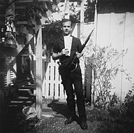 Oswald is pictured posing in a backyard. He holds rifle in his left hand and a leftist publication in his right.