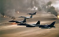عملیات طوفان صحرا. بر فراز چاه‌های نفت کویتی که درحال سوختن در آتش هستند. دو اف-۱۵ئی (مشکی) همراه با یک اف-۱۵ ایگل (سفید) و دو اف-۱۶ (سرمه‌ای) نیروی هوایی آمریکا