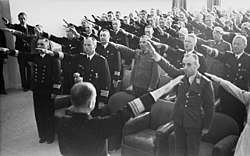 Fotografi av dusinvis av offiserer i Wehrmacht, stående i et rom, mens de gjør Hitler-hilsen