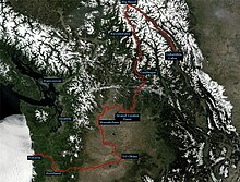 Modified satellite view of the Columbia River watershed showing the course of the river in red from Columbia Lake in British Columbia, Canada, to Astoria, Oregon, in the United States. The maps show that the river, although flowing on average in a southwesterly direction from source to mouth, changes direction sharply from northwest to south at Big Bend in Canada, from south to west near Grand Coulee Dam in Washington, from west to south near Wenatchee, Washington, and from south to west near the Tri-Cities area in Washington.