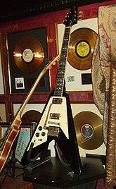 A color photograph of a black Gibson Flying V guitar