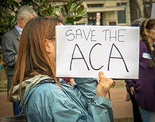 Woman holding sign that says "Save the ACA", at a rally in Washington D.C..