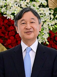 Naruhito wearing a black business suit and a light blue tie