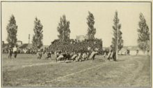 A tan and black blurry picture of two groups of men playing football with little protective equipment