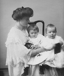 Photograph of a woman holding two young children on her lap