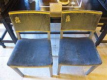 two simple chairs with cloth-covered seats and backs with the initials E R II