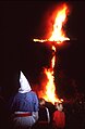 Klansmedlem med hvid hætte betragter brændende kors, et traditionelt KKK-symbol, sammen med sine børn på en bondegård i Ohio i 1987