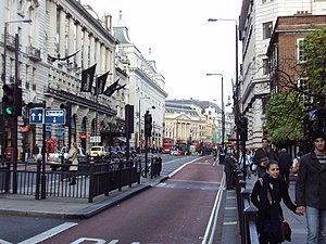 Street picture of Piccadilly with bus lane, road signs and the Meridien Hotel. Piccadilly Circus is in the background.