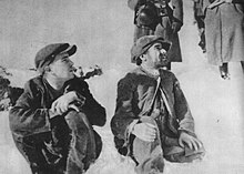 Two men in caps, sitting in the snow