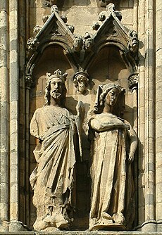 Stone sculptures of King Edward (left) and Queen Eleanor (right) at Lincoln Cathedral. Both figures are underneath triangular enclosures, and King Edward is depicted taller than his wife.
