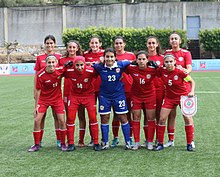 Lineup of eleven players of the Lebanon women's national under-20 football team. The outfield players are wearing red kits, and the goalkeeper is wearing a blue kit.