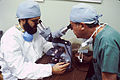 Un pathologista examine un section texito pro evidentia de cellulas cancerosus interea un chirurgista observa