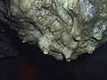 Mineralized water drop forming at bottom of stalactites