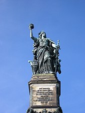 Spomenik stoječe ženske s krono v eni roki in mečem v drugi