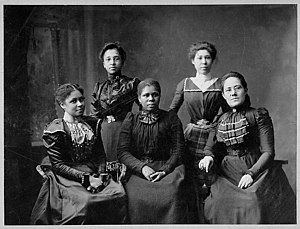 Archival photograph of five women seated together